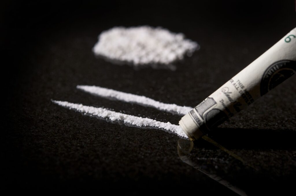 Closeup shot of lines of cocaine with rolled dollar bill with a reflection on a table