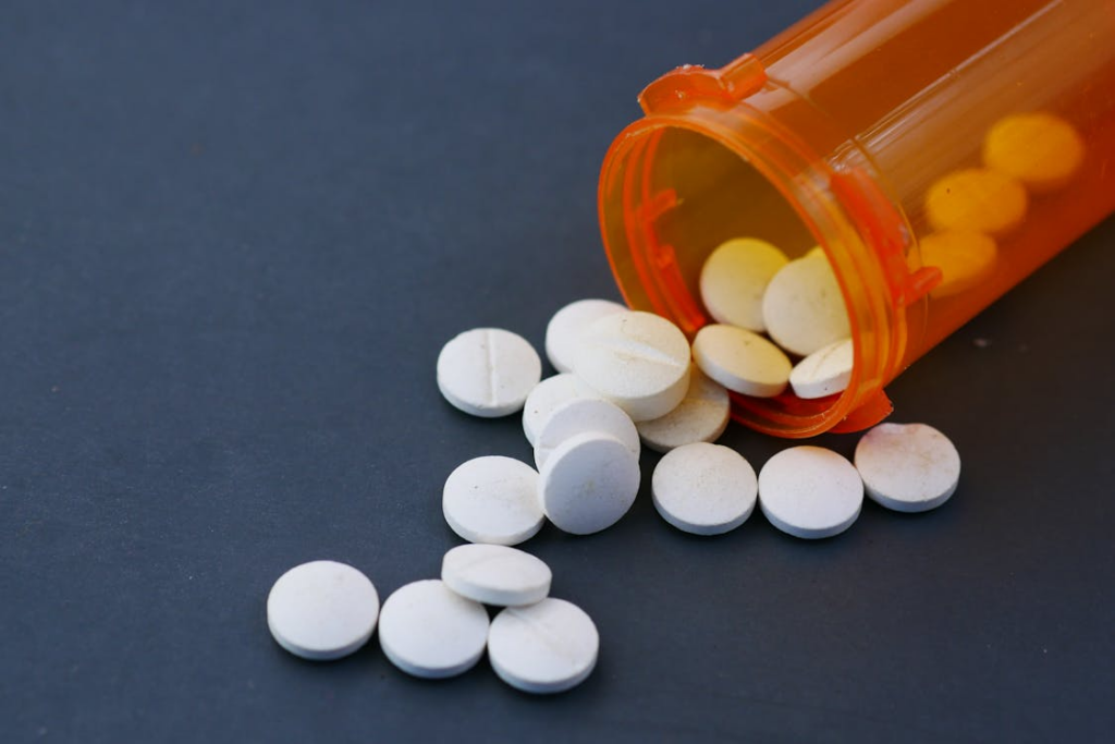 picture shows white pills scattered from an orange prescription bottle.